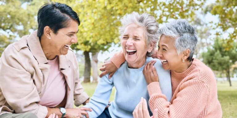 Three Elderly Women Laughing Together in a Park at an Independent Living Facility