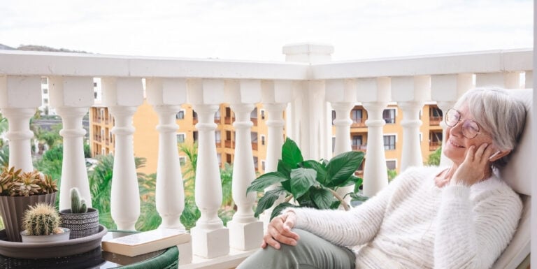 Elderly Woman Relaxing Peacefully with Music on Her Private Balcony at Independent Living Facility